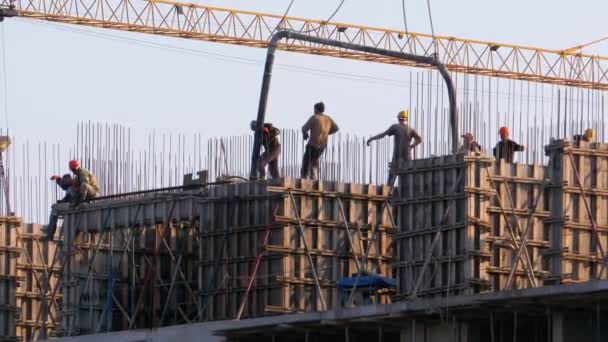 Construtores em um canteiro de obras. Guindaste em um canteiro de obras levanta uma carga. Construção de edifícios . — Vídeo de Stock