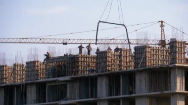 Bina İnşaat. İnşaat alanındaki bir turna yükünü kaldırıyor. İnşaat alanında çalışan işçiler