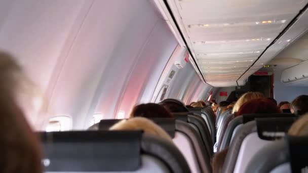 Der Salon eines Passagierflugzeugs mit Menschen, die während des Fluges in Stühlen sitzen. — Stockvideo