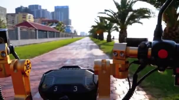 POV in sella a una bici elettrica su una pista ciclabile rossa con palme nella località turistica — Video Stock