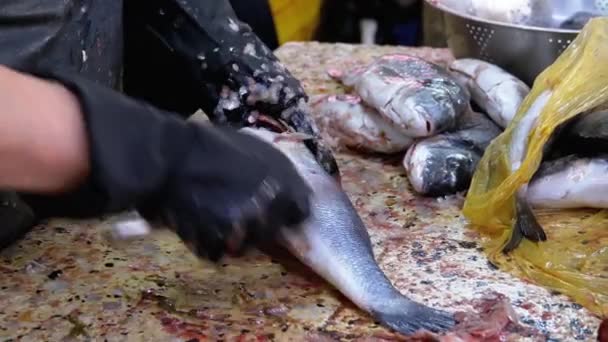 Schalen en snijden van vis in de marktkraam. Vrouw Handmatige reiniging en snijdt verse vis — Stockvideo