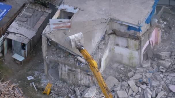 Destruindo a antiga casa de concreto usando braço mecânico de escavadeira no canteiro de obras — Vídeo de Stock