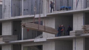 İnşaat alanındaki inşaatçılar. İnşaat alanındaki turna yükünü kaldırıyor. Yapı Yapımı.
