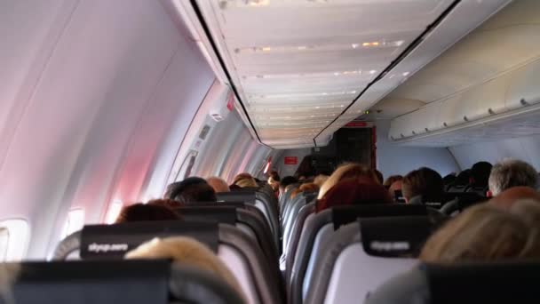 Салон пассажирского самолета с людьми, сидящими в креслах во время полета . — стоковое видео
