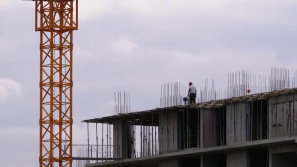 Bouwers op de rand van een wolkenkrabber in aanbouw. Werknemers op een bouwplaats. — Stockvideo