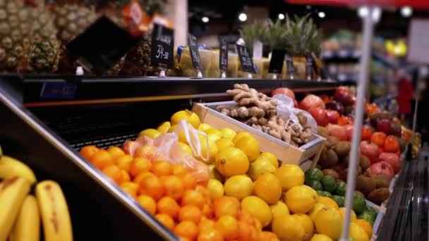 Département des fruits avec des étiquettes de prix au supermarché et les acheteurs marchant par — Video