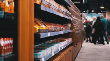 Süpermarkette çeşitli ürünlerle sıralar ve raflar. Alıcılar Ürünü Seçer.