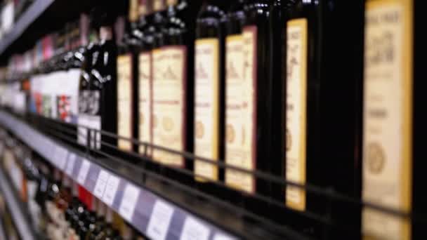 Righe e Scaffali di Vino in Bottiglia con cartellini prezzi su vetrina in Sfocatura. Vendita di alcolici nel supermercato . — Video Stock
