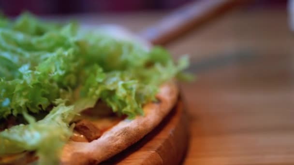 Pizza på en träbricka på ett bord i en restaurang Närbild. Detaljerad översikt över ingredienser — Stockvideo