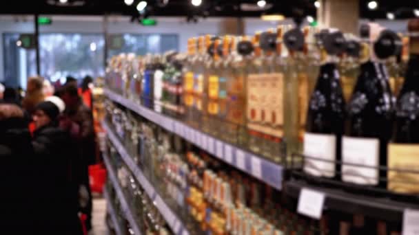 Alkohol eladás a szupermarketben. A palackozott alkohol sorai és polcai a kirakatban — Stock videók
