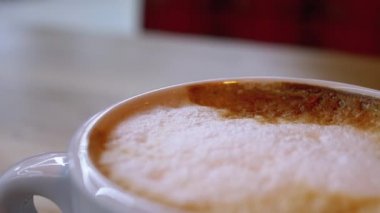 Restorandaki tahta masada beyaz köpüklü bir bardak Cappuccino. Yakın plan.