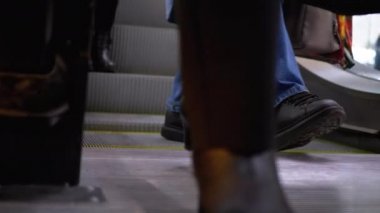 Peoples Feet, alışveriş merkezindeki asansörden aşağı iniyor. Alışveriş merkezinde müşteriler yürüyen merdivende.