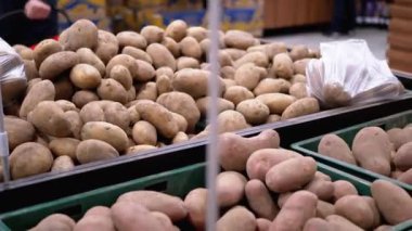 Süpermarketin vitrininde patates sepetleri ve yanından geçen müşteriler.
