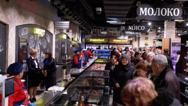 Multidão de compradores em um supermercado caminha entre fileiras de mercadorias. Vendedores ficam atrás das prateleiras — Vídeo de Stock