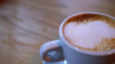 Restorandaki tahta masada beyaz köpüklü bir bardak Cappuccino. Yakın plan.