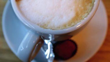Restorandaki tahta masada beyaz köpüklü bir bardak Cappuccino. Yakın plan.