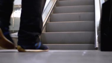 Alışveriş merkezinde yürüyen merdiven asansöründe yürüyen insan bacakları. Alışveriş merkezinde müşteriler yürüyen merdivende.