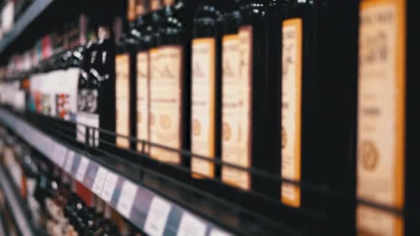 Venta de Alcohol en Supermercado. Filas y estantes de vino embotellado con etiquetas de precio en un escaparate en Blur — Vídeos de Stock