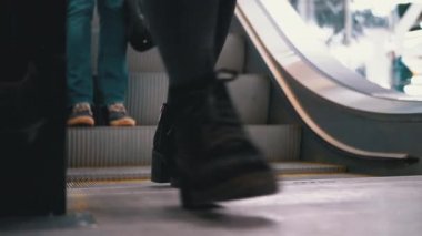 Peoples Feet, alışveriş merkezindeki asansörden aşağı iniyor. Alışveriş merkezinde müşteriler yürüyen merdivende.