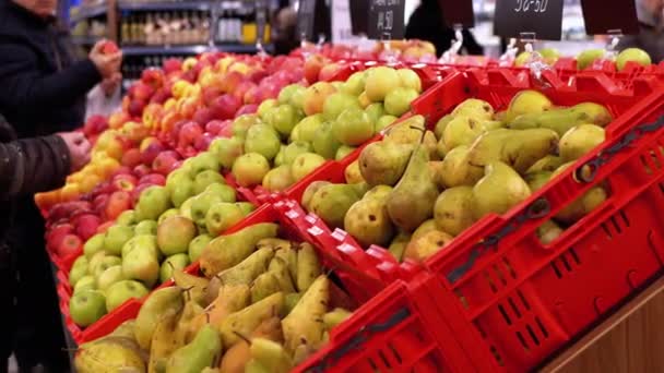 Fruits avec des étiquettes de prix sur une vitrine dans un supermarché et les acheteurs marchant par . — Video