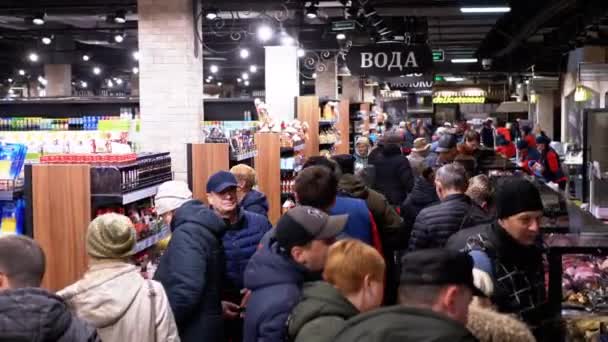 Une foule d'acheteurs dans un supermarché se promène entre des rangées de marchandises. Les vendeurs se tiennent derrière les étagères — Video