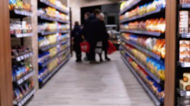 Süpermarkette çeşitli ürünlerle sıralar ve raflar. Alıcılar Ürünü Seçer.