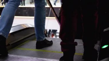 Alışveriş merkezinde yürüyen merdiven asansöründe yürüyen insan bacakları. Alışveriş merkezinde müşteriler yürüyen merdivende.