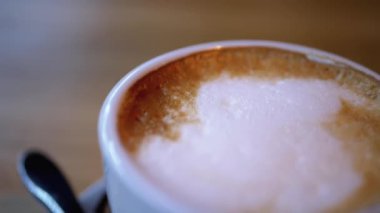 Restorandaki tahta masada beyaz köpüklü bir bardak Cappuccino. Yakın plan.