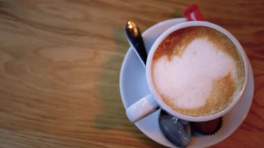 Restorandaki tahta masada beyaz köpüklü bir bardak Cappuccino. Yakın plan.