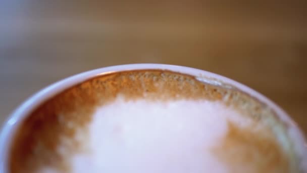 Kupa Cappuccino fehér habbal a fa asztalon az étteremben. Közelkép — Stock videók