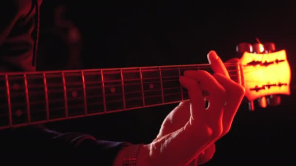 Tocando uma guitarra acústica com fundo vermelho e preto — Vídeo de Stock