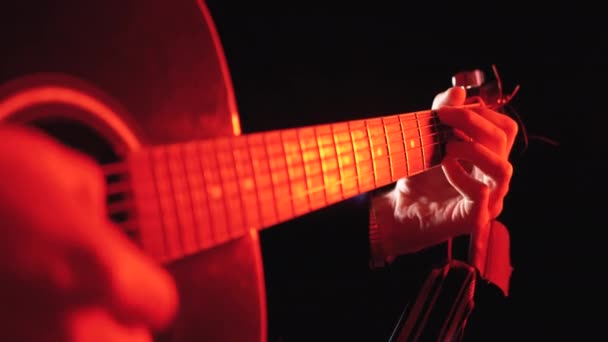 Tocando uma guitarra acústica com fundo vermelho e preto — Vídeo de Stock