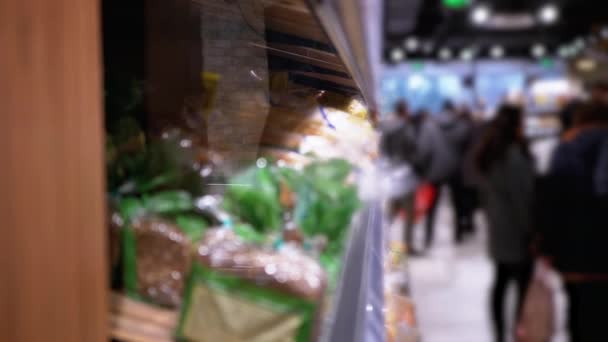 Ряды и полки с различными хлебом в супермаркете. Покупатели выбирают товар — стоковое видео