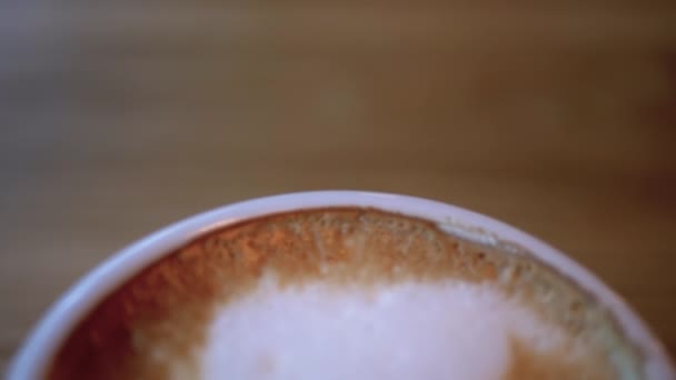 Copa de Cappuccino con Espuma Blanca en la Mesa de Madera del Restaurante. Primer plano — Vídeo de stock