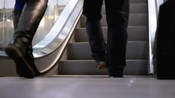 Pernas de pessoas que se movem em um elevador de escada rolante no shopping. Pés de compradores em escada rolante no centro comercial — Vídeo de Stock