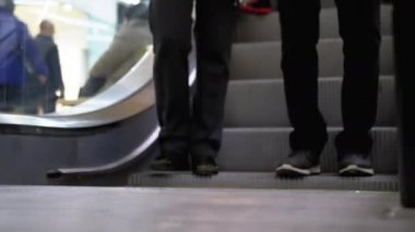 Alışveriş merkezinde yürüyen merdiven asansöründe yürüyen insan bacakları. Alışveriş merkezinde müşteriler yürüyen merdivende.