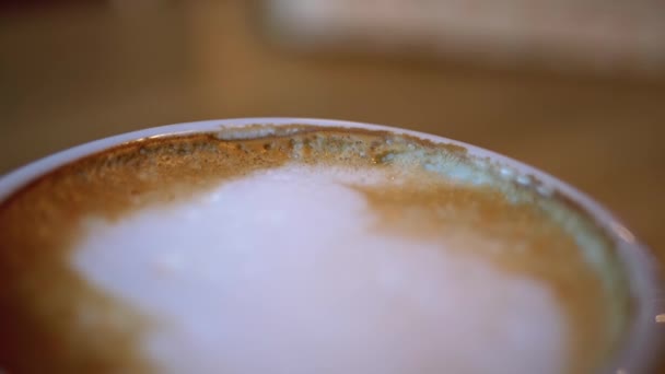 Kopje Cappuccino met witte schuim op de Houten Tafel in het Restaurant. Close-up — Stockvideo