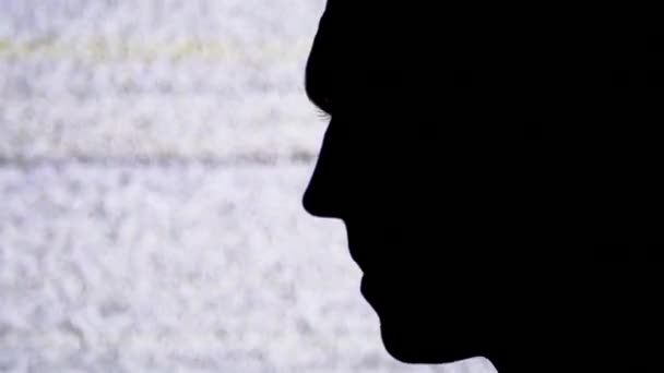 Profiel silhouet van een mannelijk gezicht op een tv-scherm met witte ruis en interferentie achtergrond. — Stockvideo