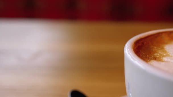 Restorandaki tahta masada beyaz köpüklü bir bardak Cappuccino. Yakın plan. — Stok video