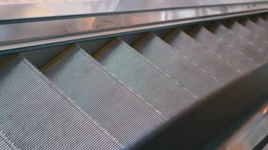 İnsanlar AVM 'de yürüyen merdivenden aşağı inip parmaklıkları tutuyorlar..