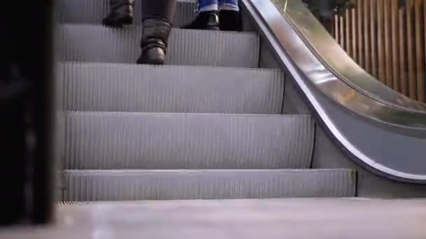 Alışveriş merkezinde yürüyen merdiven asansöründe yürüyen insan bacakları. Alışveriş merkezinde müşteriler yürüyen merdivende. — Stok video
