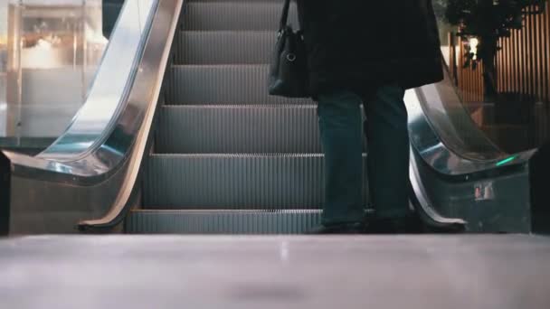 Pernas de pessoas que se movem em um elevador de escada rolante no shopping. Pés de compradores em escada rolante no centro comercial — Vídeo de Stock