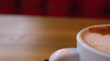 Restorandaki tahta masada beyaz köpüklü bir bardak Cappuccino. Yakın plan.