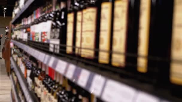 Filas y estantes de vino embotellado con etiquetas de precio en un escaparate en Blur. Venta de Alcohol en Supermercado . — Vídeos de Stock