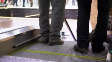 Alışveriş merkezinde yürüyen merdiven asansöründe yürüyen insan bacakları. Alışveriş merkezinde müşteriler yürüyen merdivende.