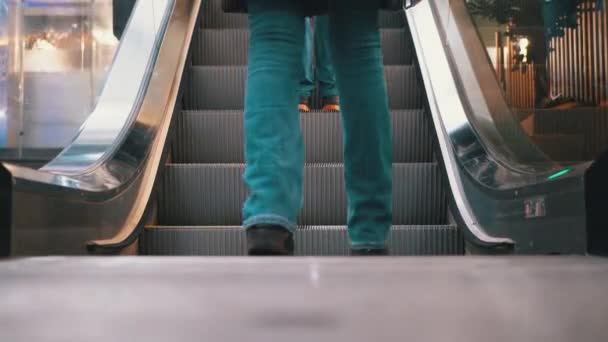 Pernas de pessoas que se movem em um elevador de escada rolante no shopping. Pés de compradores em escada rolante no centro comercial — Vídeo de Stock