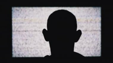 İsimsiz bir Mans Head 'in Silueti Beyaz Statik Gürültü ve TV Parazitini İzliyor
