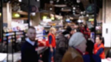 Bir süpermarket tezgahındaki müşteri kalabalığı kasanın önünde kuyruktalar.