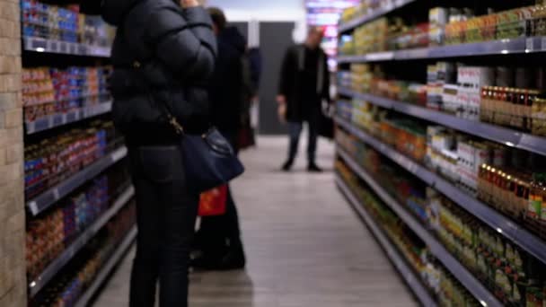 Рядки та полиці з різними продуктами в супермаркеті. Покупці Виберіть товар . — стокове відео