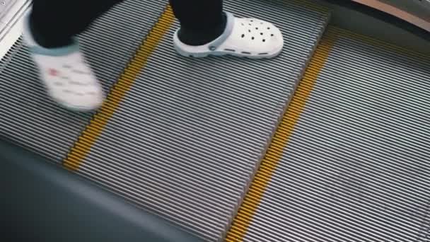 Menschen gehen die Rolltreppe in der Mall hinunter, die das Geländer hält. — Stockvideo